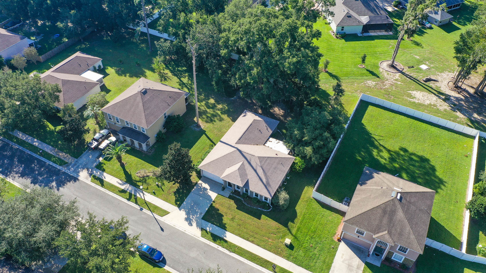 drone shot of neighborhood with three homes and trees